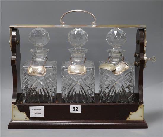 A PB & S three decanter tantalus with five silver labels - Vodka, Gin, Scotch, Whiskey